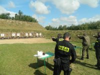 Obraz przedstawia funkcjonariuszy na strzelnicy na  turnieju strzeleckim w Hajnówce