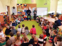 Obraz przedstawia policjantów na tle dzieci w Szkole Podstawowej w Kobylinie Borzymach