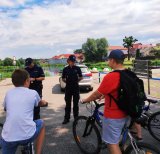Obraz przedstawia policjantów rozmawiających z rowerzystami