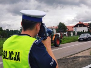 Obraz przedstawia policjanta dokonującego kontroli w miejscowości Ruś