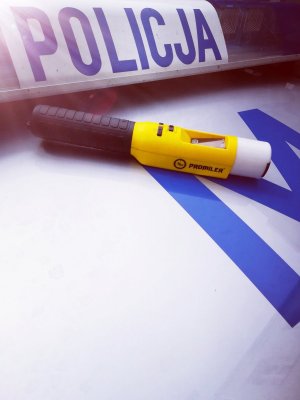 Fotografia przedstawia urządzenie do pomiaru zawartości alkoholu w wydychanym powietrzu o nazwie promiler leżące na radiowozie policyjnym.