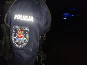 obraz przedstawia ramię mężczyzny w mundurze z napisem policja