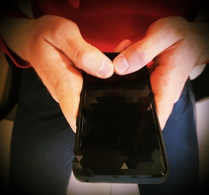 obraz przedstawia dłonie trzymające aparat telefoniczny