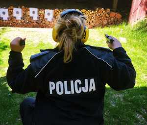 obraz przedstawia policjantkę przygotowującą się do strzelania