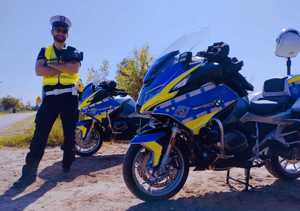obraz przedstawia policjanta stojącego obok motocykli