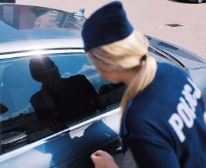 obraz przedstawia policjantkę patrzącą na pojazd