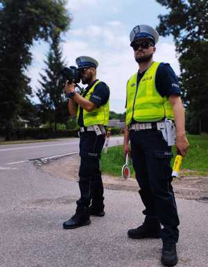 obraz przedstawia policjantów obserwujących drogę