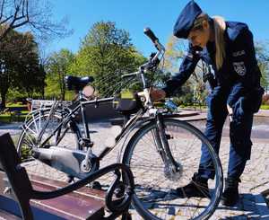 obraz przedstawia policjantkę patrzącą na rower
