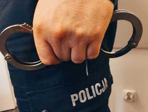 obraz przedstawia dłoń policjanta trzymającego kajdanki